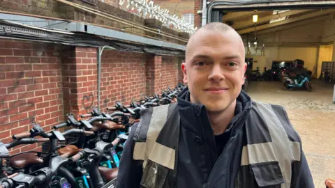 A man is in a hi viz and smiling and looking into the camera