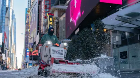 Getty Images A worker clears snow in Times Square
