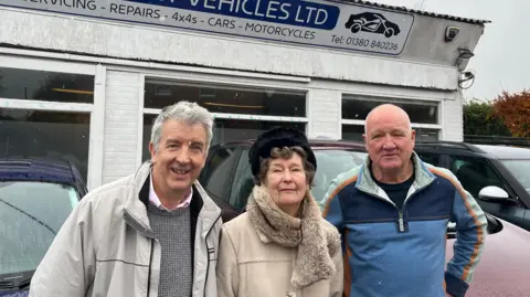 Bill Donald, Ann Blunden, and Wiltshire councillor Philip Whitehead  standing together in front of Urchfont Vehicles Ltd