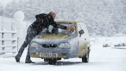 Owen Humphreys/PA Wire A man scrapes ice off his 3 wheel Reliant Robin in Cumbria