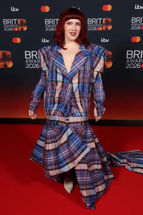 Getty Images CMAT on the red carpet in a tartan dress with powerful shoulder pads and a full skirt.