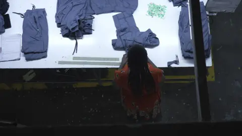Overhead image of a worker at a table inspecting finished garments.