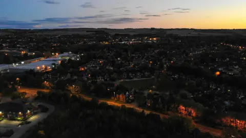 Getty Images/Paul Brown A bird's eye view of Wantage at dusk, with street lights illuminating many streets 