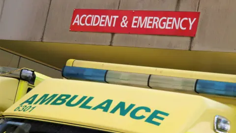 The top of a yellow NHS ambulance showing the ambulance sign below a red sign saying accident and emergency