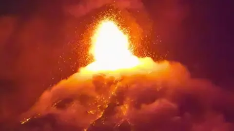A screengrab taken from CCTV footage at nighttime shows lava bursting from the crater of the Fuego volcano