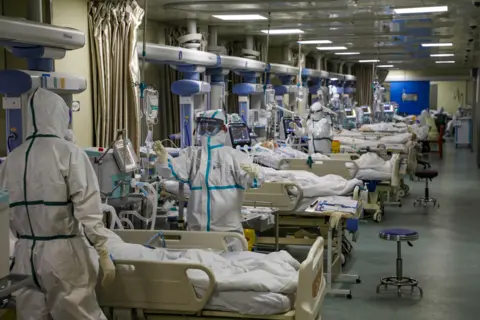 China Daily via Reuters Medical workers in protective suits attend to Covid-19 patients at an intensive care unit in Wuhan, Hubei province, China, 6 February 2020