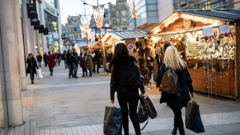 Getty Images Shoppers walk by market