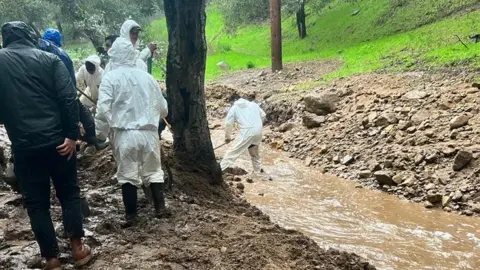 BBC Volunteers digging trenches after giant boulders and mud blocked access to some homes in California