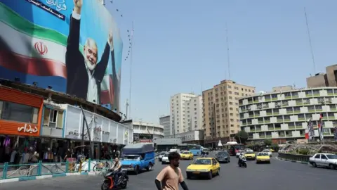 EPA cars and people on a Tehran street displaying a portrait of former Hamas leader Ismail Haniyeh (file photo)