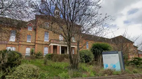 A Google Street image of the outside of a red brick hospital. It says "Farnham Road Hospital" on the sign.