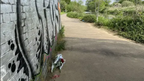 Kate Bradbrook/BBC Flowers left in tribute on river path