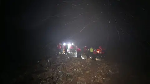 Wasdale MRT People in red coats with head torches walk through the dark and rain