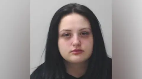 Police Scotland A mugshot of a young woman with long dark hair. 