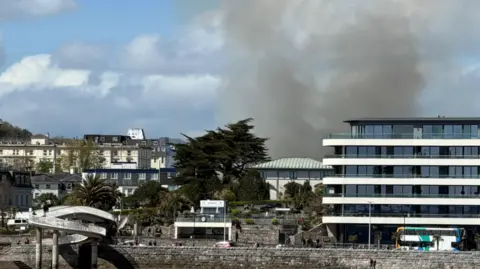 Black smoke bellowing from behind a building in Torquay. 