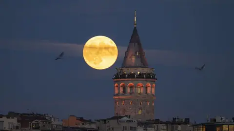 Picha za Getty Mwezi Kamili hupanda nyuma ya Mnara wa Galata huko Istanbul, Turkiye