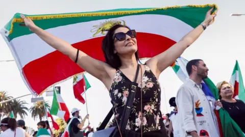 A woman holds a flag while attending a rally against Iran's ruling establishment in Los Angeles, California, U.S. on 28 February 2026