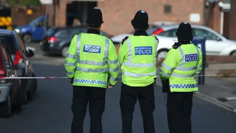 Getty Images Three police officers at a cordon