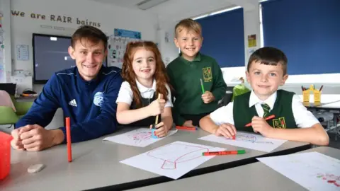 Football coach Danny Strachan with school pupils.