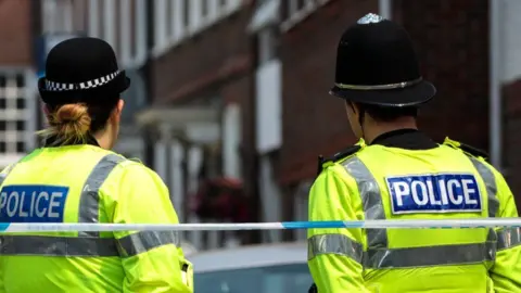 Getty Images Female and male officers behind police tape