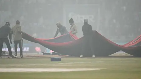 AFP via Getty Images Groundsmen cover the pitch during the fourth Twenty20 international cricket match between India and South Africa at the Ekana Cricket Stadium in Lucknow on 17 December 
