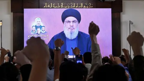 EPA Hezbollah leader Hassan Nasrallah delivers a speech via a screen at a memorial ceremony for Taleb Abdallah, killed in an alleged Israeli air strike (19/06/24)