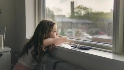 Getty Images A girl looking out of a window