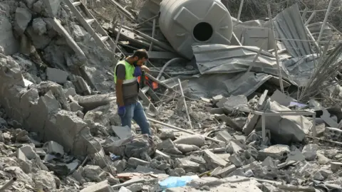 An emergency worker looks through rubble in the aftermath of an airstrike on Ansar in Lebanon