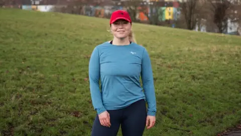 Katie Grant Image of Maria Mcmenemy. She is outside on a run in Bristol. In the picture, she is stood up, looking directly at the camera and smiling.