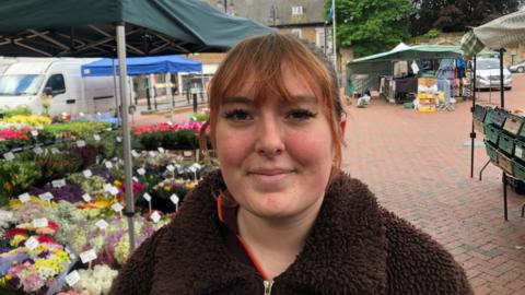 Isla Staveley standing next to a flower stall in Ely Market