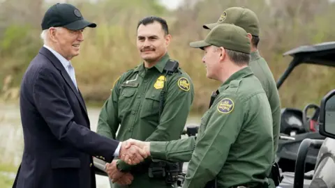 Reuters President Joe Biden shakes hands with a US border official