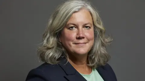 UK Parliament Headshot of Heidi Alexander, who has shoulder-length grey hair and wears a navy blazer and a mint green top.