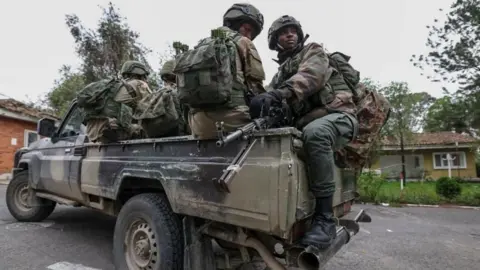 EPA-Fe/Rex/Shutterstock M23 rebel in GOMA (File Photo); Soldiers sit on the back of a truck. 