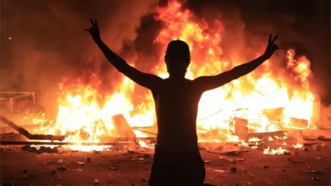 EPA Protestor silhouetted against flames in Karbala, Iraq (28/10/19)