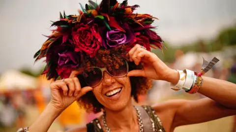 PA Media A woman wearing a flower headdress during the Glastonbury Festival