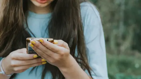 Getty Images A girl using the cell phone outdoors - stock photo