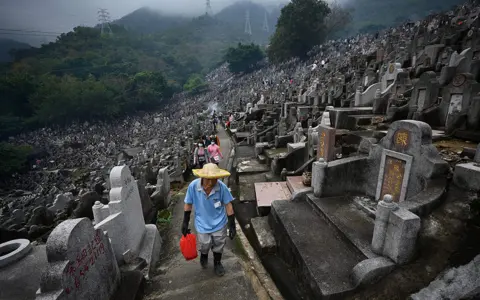 Peter Parks / AFP People walk through the Diamond Hill Cemetery in Hong Kong on 5 April 2023