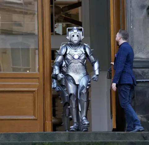 PA Media A curator opens a museum door for a cyberman