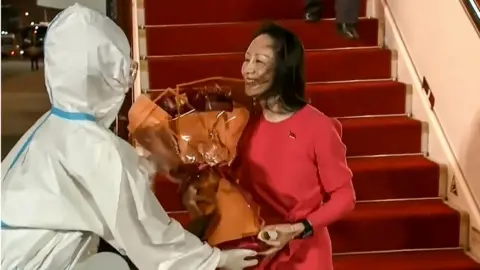 AFP via Getty Images This screen grab made from video released by Chinese state broadcaster CCTV shows Huawei executive Meng Wanzhou receiving flowers after she arrived following her release