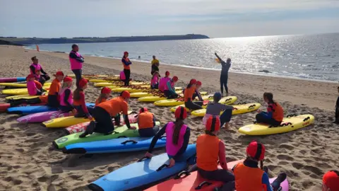 Carlyon Bay Surf Life Saving Club Young people with their surfboards listening to an instructor.