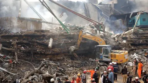EPA Rescuers search through the rubble at Gul Plaza in Karachi, Pakistan, 19 January 2026. 