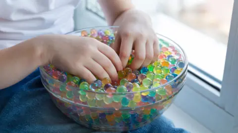 Getty Images Child playing with water beads. The beads are of different colours and in a clear bowl. The hands of the child can been seen.