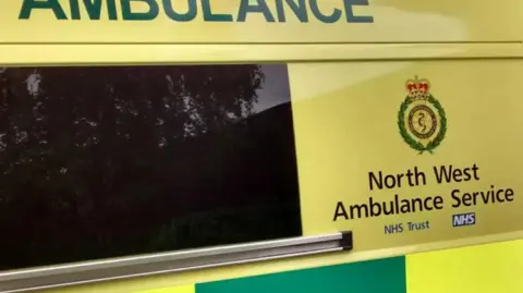 PA Media Close up of a North West Ambulance Service van with its signature yellow and green colours.
