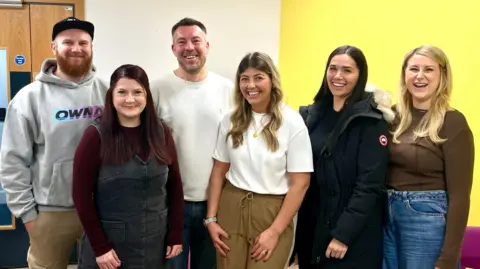 A small group of parents standing together for the camera in a children's classroom