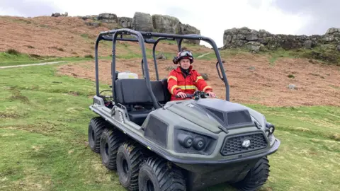 An eight-wheel Argocat all-terrain vehicle vehicle with a firefighter in a red and yellow boiler suit at the wheel 