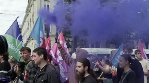 Purple smoke billows from a flare during a protest in Nantes