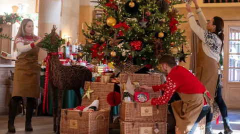 Staff at Highgrove prepare a large Christmas tree with wicker-style hampers of presents underneath it