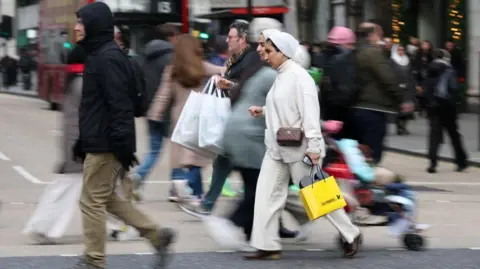 People walk with shopping bags on Oxford Street during Boxing Day sales, in London.