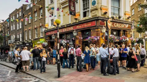 Getty Images People standing outside a pub named The Crown