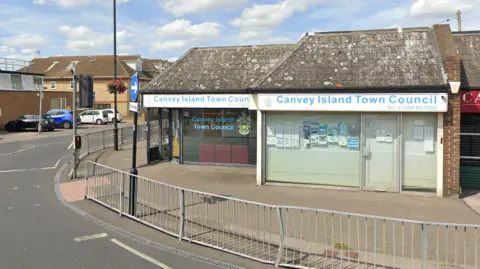 Google The Canvey Island Town Council offices. They are based in a single-storey building on the side of a road. The building has "Canvey Island Town Council" signs and a crest in the window.