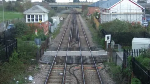 Dorset Council Railway lines stretching into the distance with buildings either side and a road bridge over the railway line in the distance.